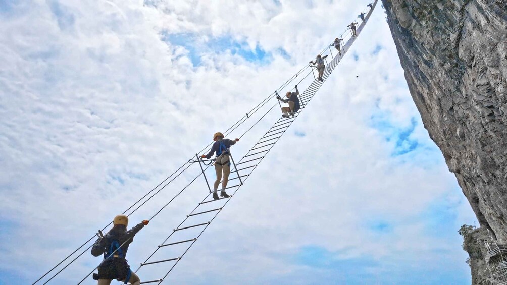 Un grupo de personas cruzando un puente colgante sobre un cañón. 1