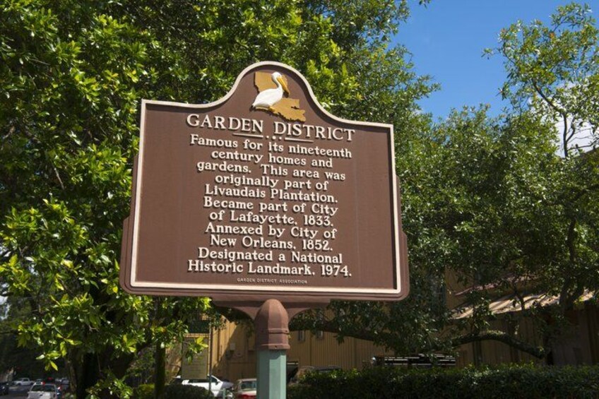 A historical sign about the Garden District, mentioning its 19th-century homes and gardens, part of the Livaudais Plantation, annexed by City of New Orleans in 1852, and designated a National Historic Landmark in 1974. 1