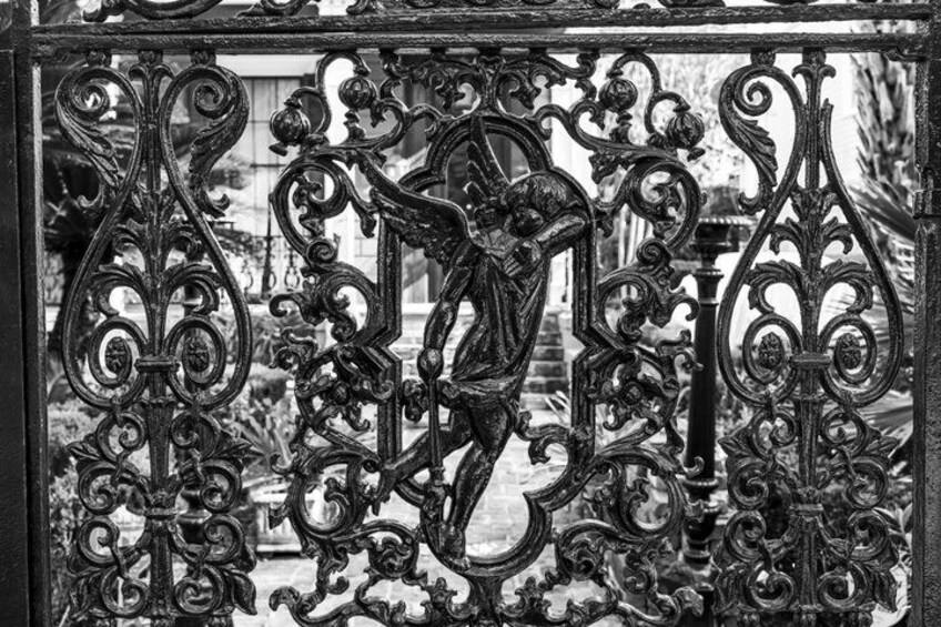 A black and white ornate iron gate with intricate designs and a figure of a person. 3