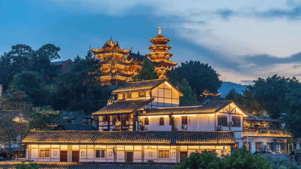 A traditional Chinese pagoda with multiple tiers, illuminated by warm lighting, surrounded by lush greenery and traditional buildings. 3