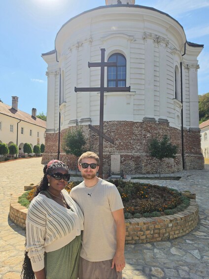 A historic building with a prominent cross, a stone courtyard, and a brick wall. 3