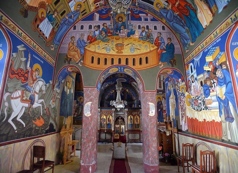 An ornate church interior with detailed frescoes, a central altar, and a chandelier. 2