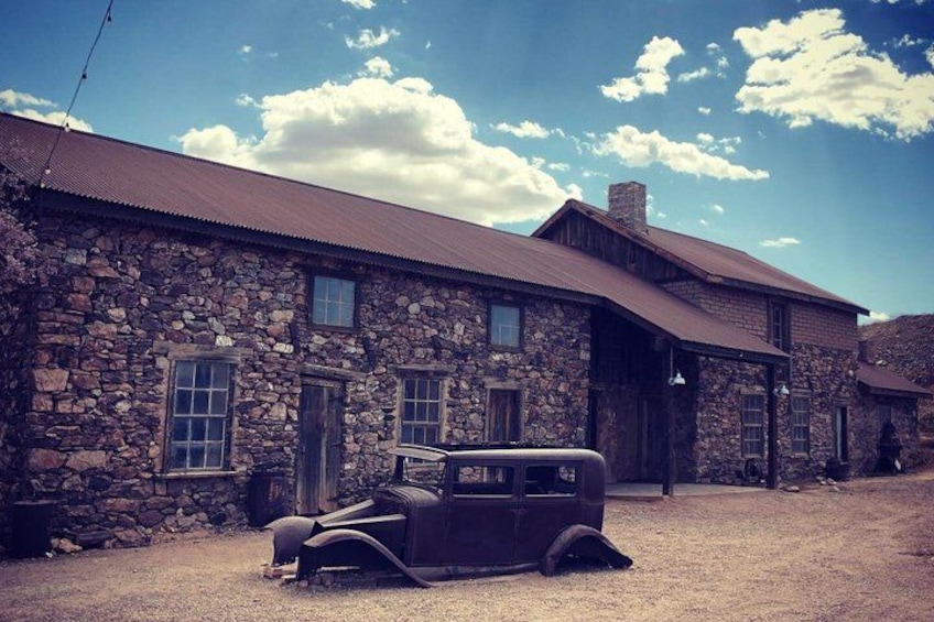 A stone building with a vintage car parked in front. 4