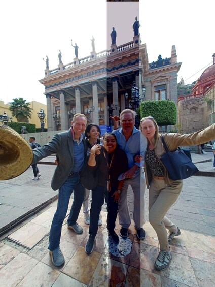 Un grupo de personas posando frente a un edificio histórico con columnas y estatuas. 3