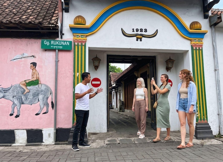 A street scene with a building entrance marked '1923,' a mural of a man on a bull, and a 'no entry' sign. 1