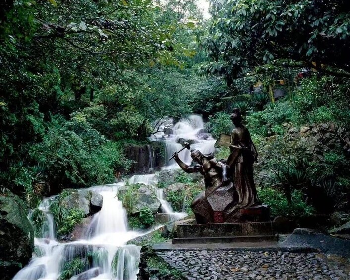 A waterfall, lush greenery, and a statue. 3