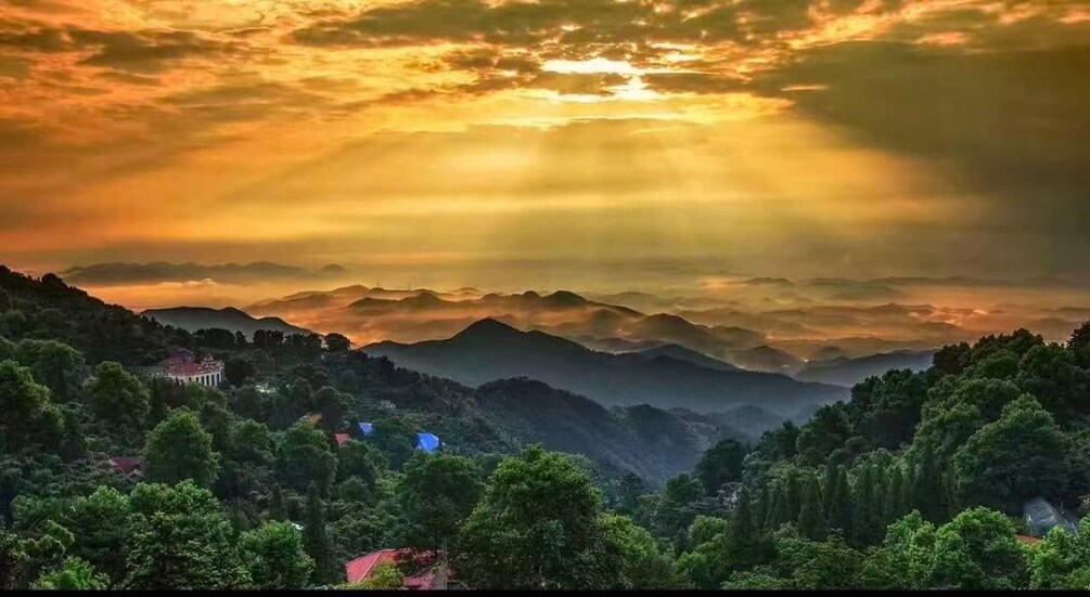 A mountainous landscape with a sunset, a village, and a prominent building. 1