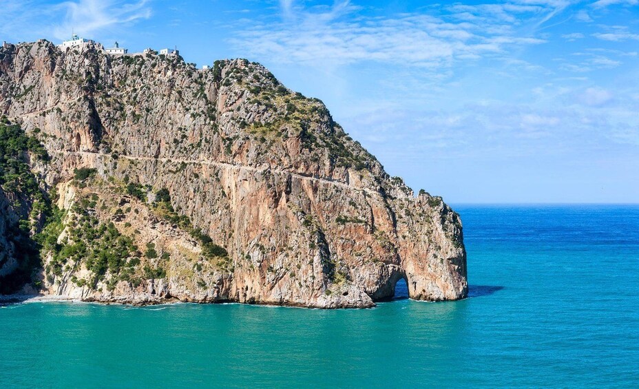 Una costa escarpada con una formación rocosa destacada y un mar azul cristalino. 2