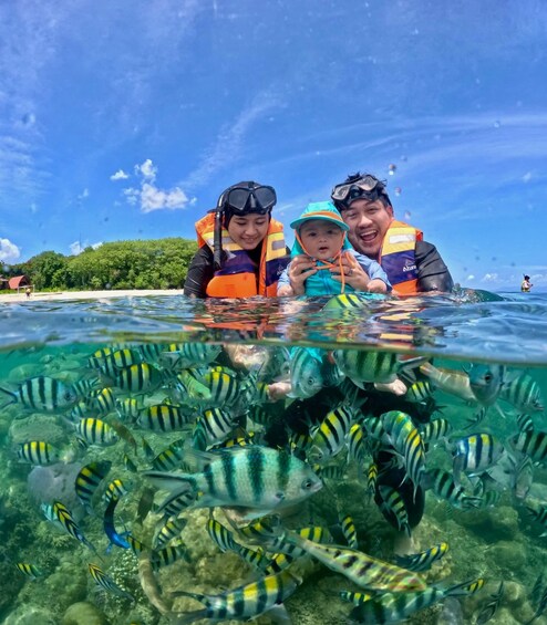 Een groep mensen snorkelt tussen tropische vissen in helder water. 3