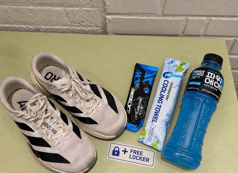 Un paio di scarpe da ginnastica bianche, una bottiglia d'acqua blu, un asciugamano rinfrescante e un cartello che indica un armadietto gratuito. 5