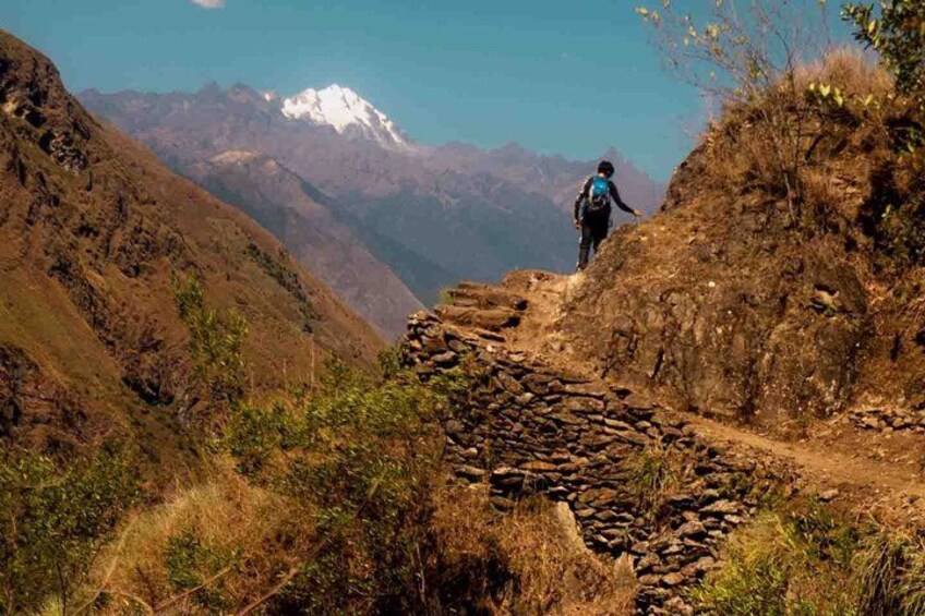 A hiker on a rocky trail with a mountainous backdrop. 2
