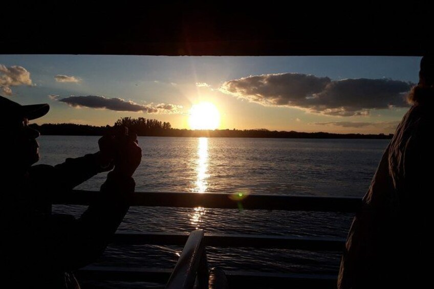 A sunset over a body of water with silhouettes of people. 3