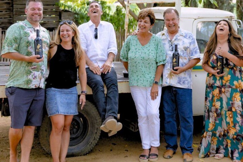 A group of people standing around a vehicle with a flatbed, holding bottles. 1