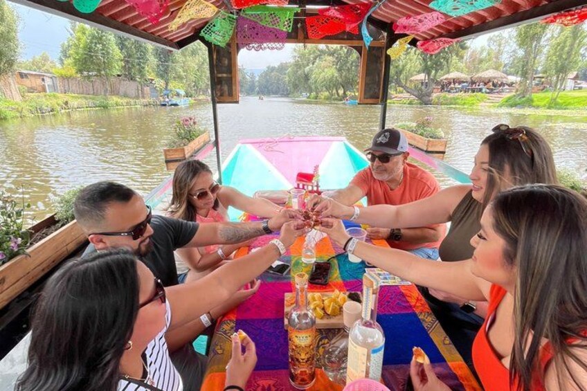 A group of people sitting around a table on a boat, holding hands in a circle. 2