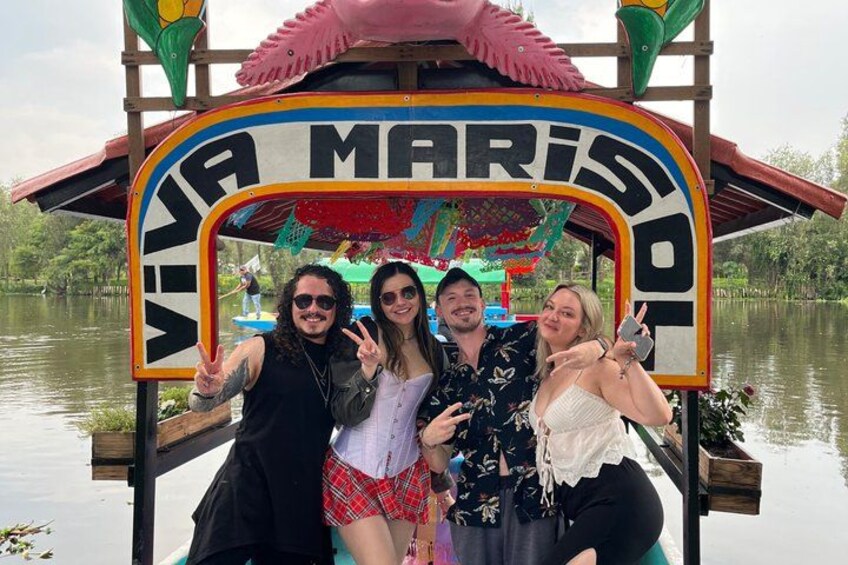 A group of people posing in front of a colorful boat with the text 'VIVA MARIS' on it. 5