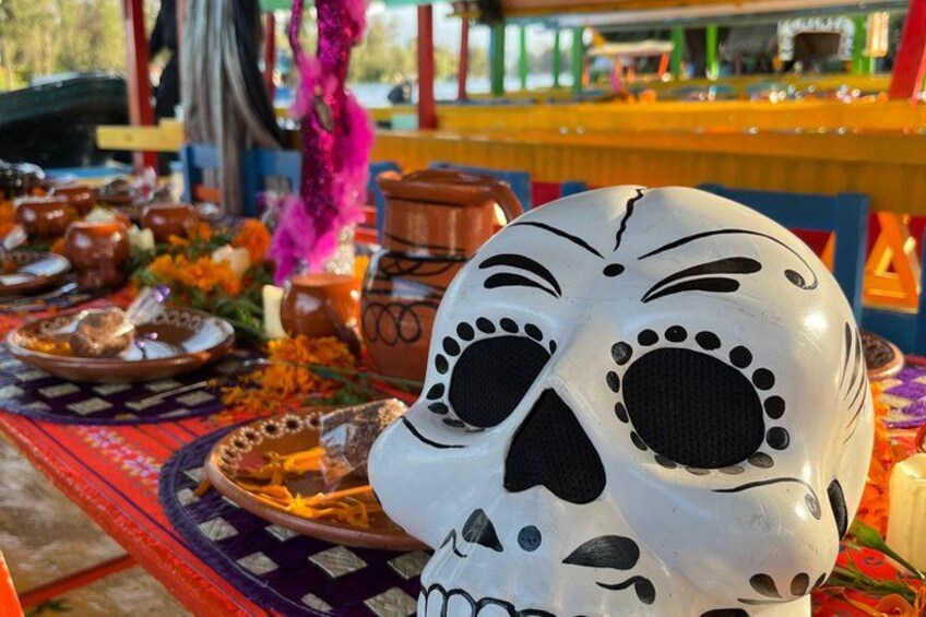 A decorated table with a skull, plates, and flowers. 3