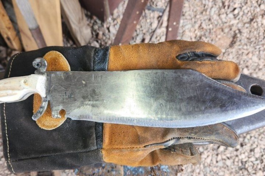 A knife with a wooden handle and a metal blade, resting on a glove. 5