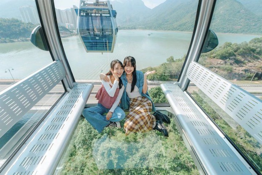 Two people sitting on a bench with a scenic view of a cable car and a lake. 2