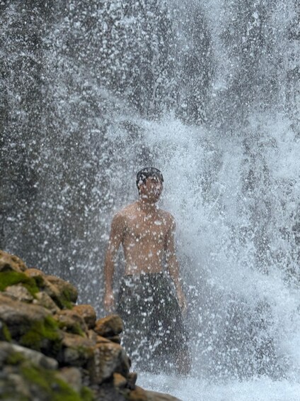 Una persona de pie frente a una cascada. 1