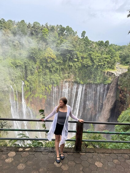 Una persona parada junto a una barandilla, con una cascada al fondo. 3