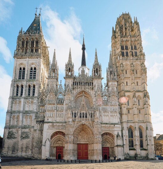 Una catedral gótica con elaborados detalles de piedra, altas agujas y una puerta principal de color rojo. 4