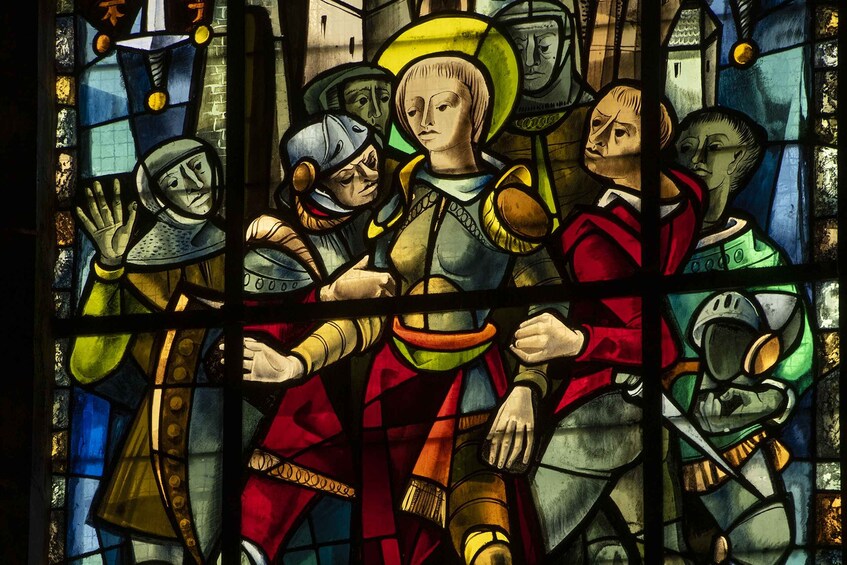 Una vidriera con figuras en armadura medieval, una cruz y el interior de una iglesia. 2