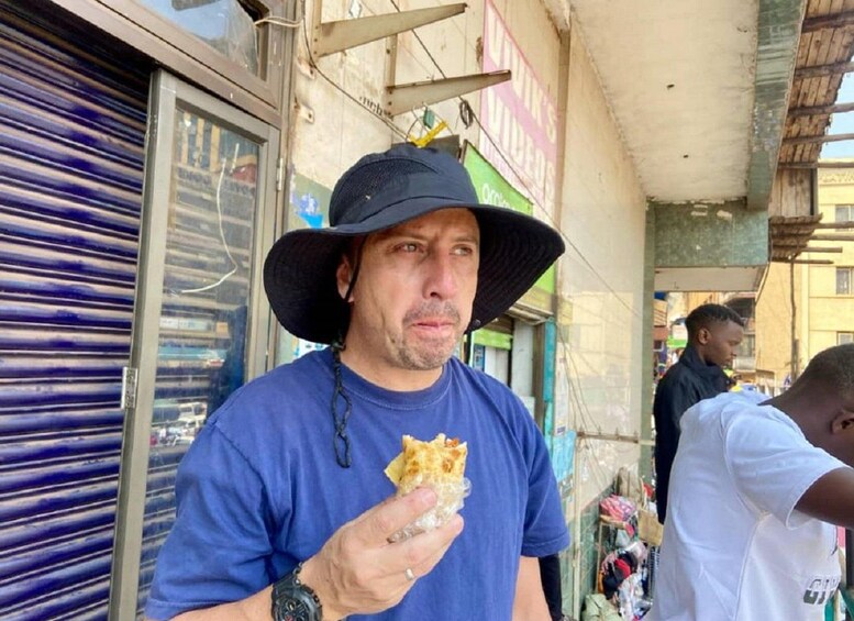 Una persona con camisa azul y sombrero de ala ancha sosteniendo un bocado. 5