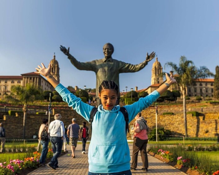 Una persona con los brazos levantados frente a una estatua. 1
