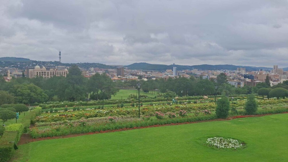 Un paisaje urbano con un parque grande al frente, que cuenta con césped cuidado y parterres de flores. 5