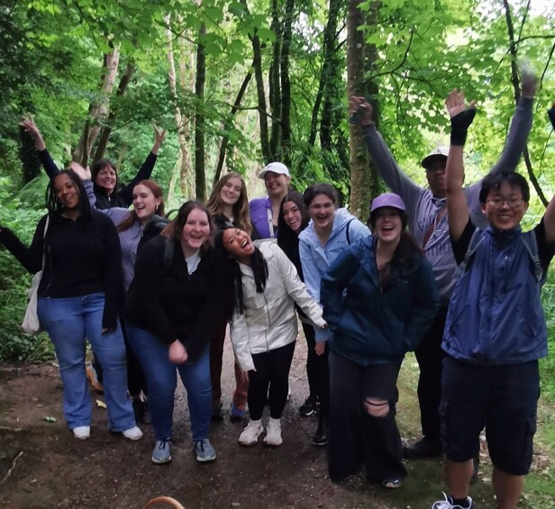 A group of people in a forested area with trees and a dirt path. 1