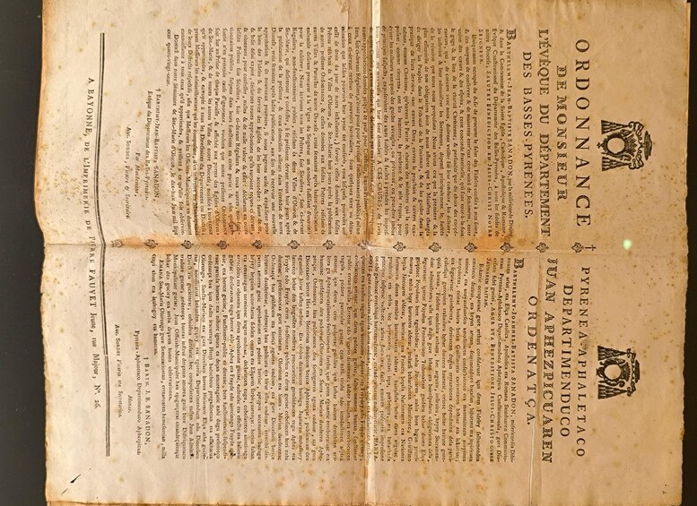 Un documento antiguo y amarillento con texto y un emblema decorativo en la parte superior. 2
