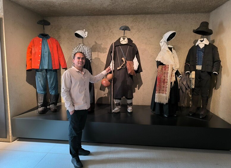A person standing in front of mannequins dressed in historical costumes. 5