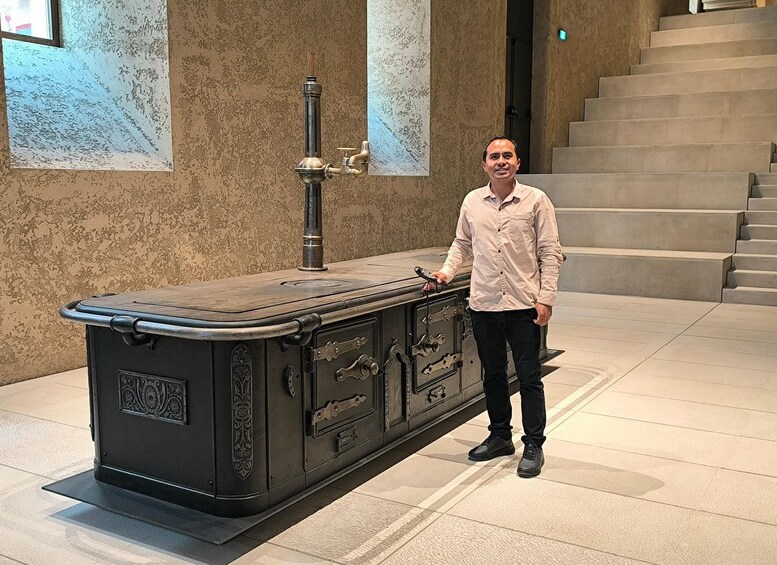 Una estufa antigua con detalles ornamentales y una persona de pie a su lado. 5