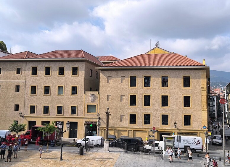 Una calle con edificios, una farmacia y vehículos estacionados. 4