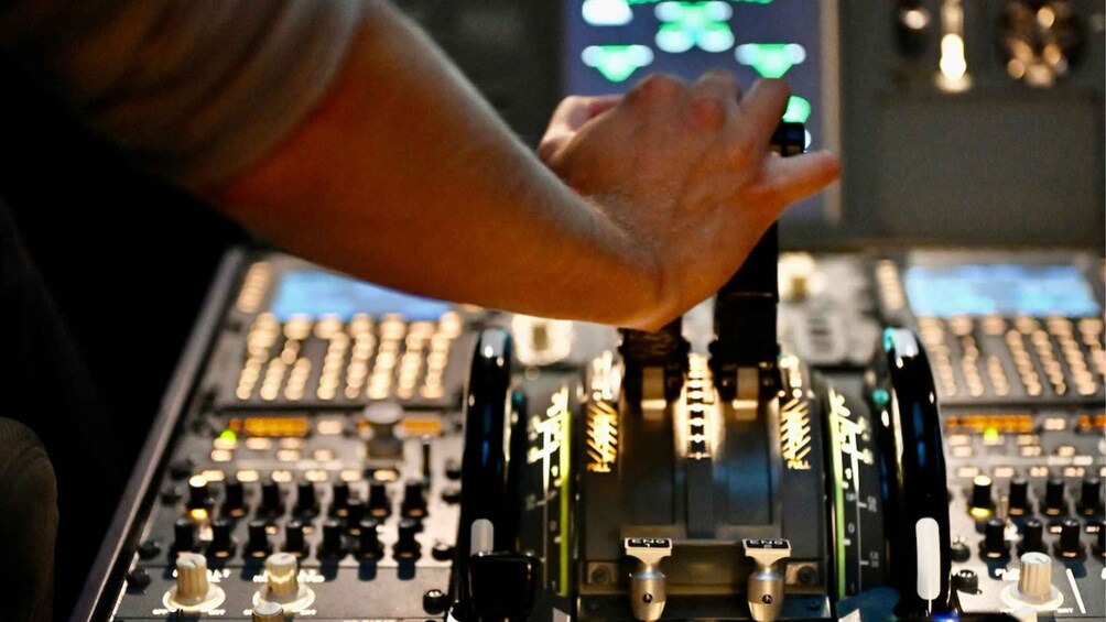 A person's hand operating a mixing console with multiple knobs and sliders. 3