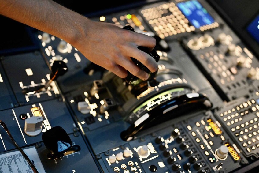 A hand adjusting knobs on a control panel with illuminated buttons and switches. 5