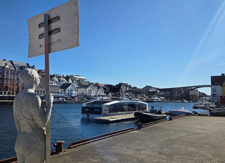 A statue, a harbor with boats, and buildings along the waterfront. 3