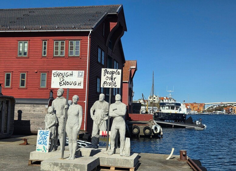 A harbor with a red building, statues, and signs about environmental issues. 2