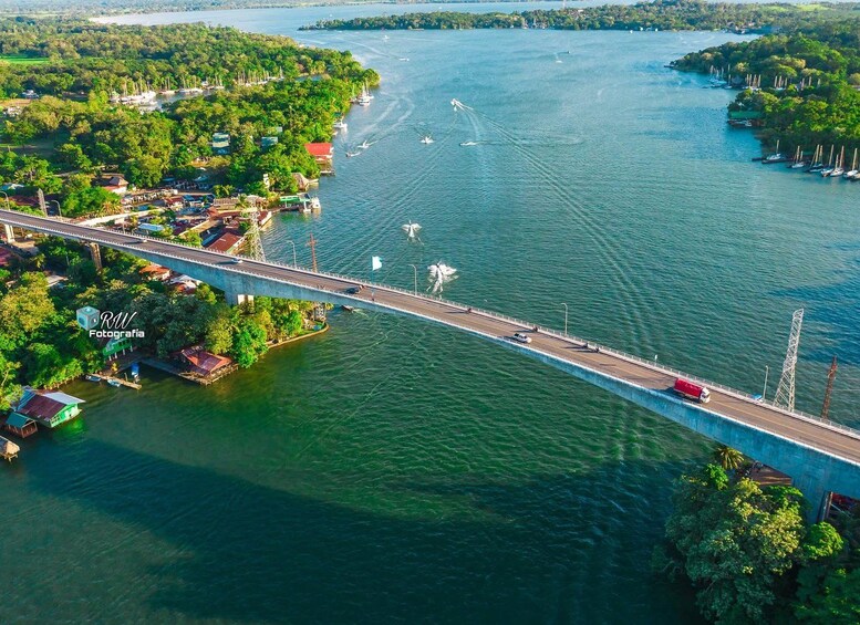 A bridge over a river with boats and a red truck on it. 1