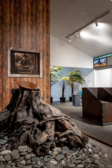 Un intérieur rustique avec un mur en bois, un tableau encadré, une souche d’arbre et une plante en pot. 4