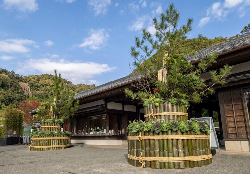 A traditional Japanese building with a tiled roof, surrounded by bamboo structures with plants. 1