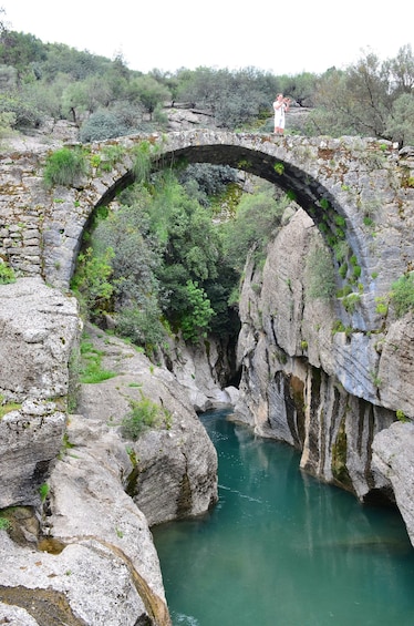 Un arco de piedra sobre un río, con vegetación a ambos lados. 2