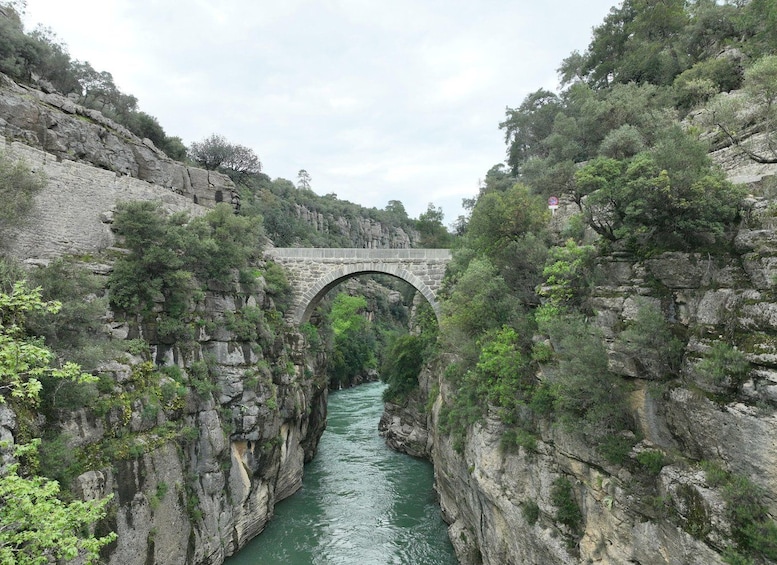 Un puente de piedra sobre un río, rodeado de riscos y vegetación. 4