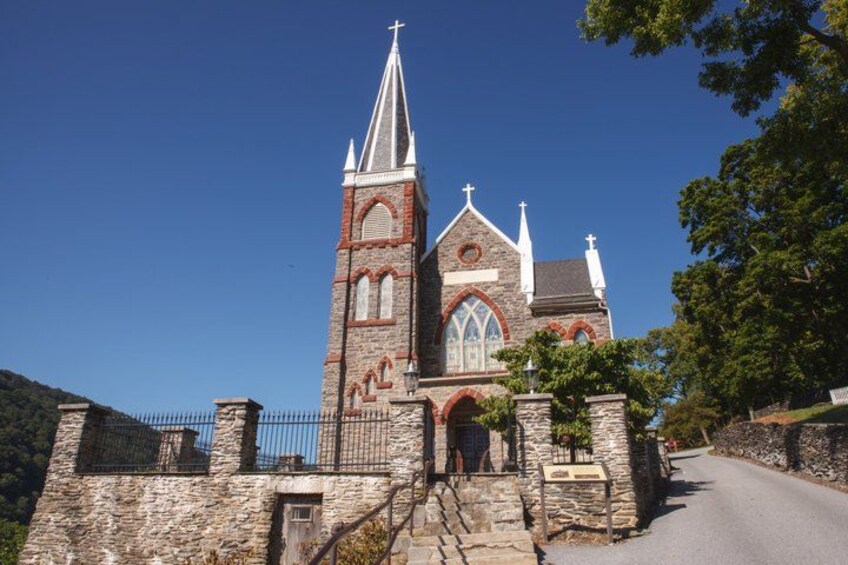 A church with a tall steeple, a stone facade, and a cross at the top. 5