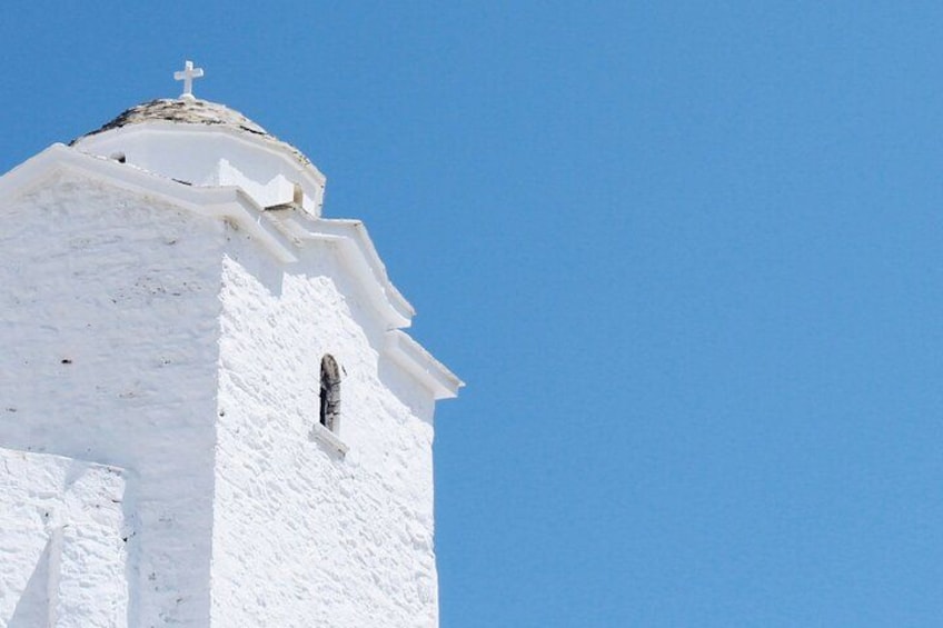 A white church with a cross on top and a clear blue sky. 3