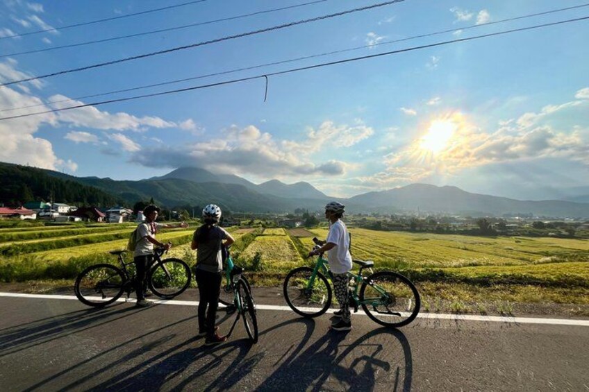 Cyclists on a road with a scenic view of mountains and fields. 2
