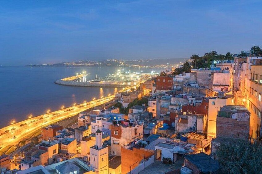 A coastal cityscape at dusk with illuminated streets and buildings. 2