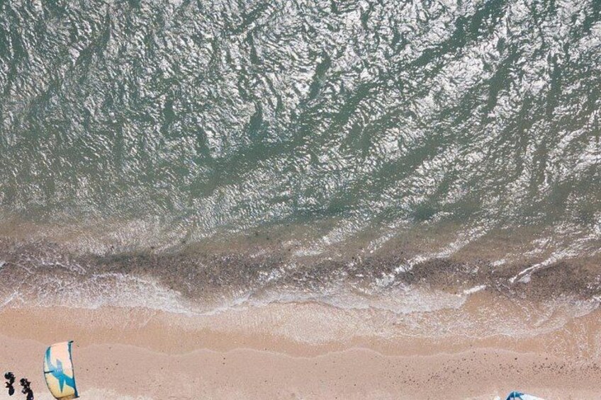 A beach with waves, sand, and a surfboard. 5