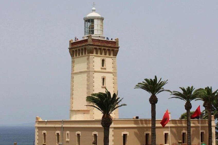 A tall tower with a dome, palm trees, and red flags. 4