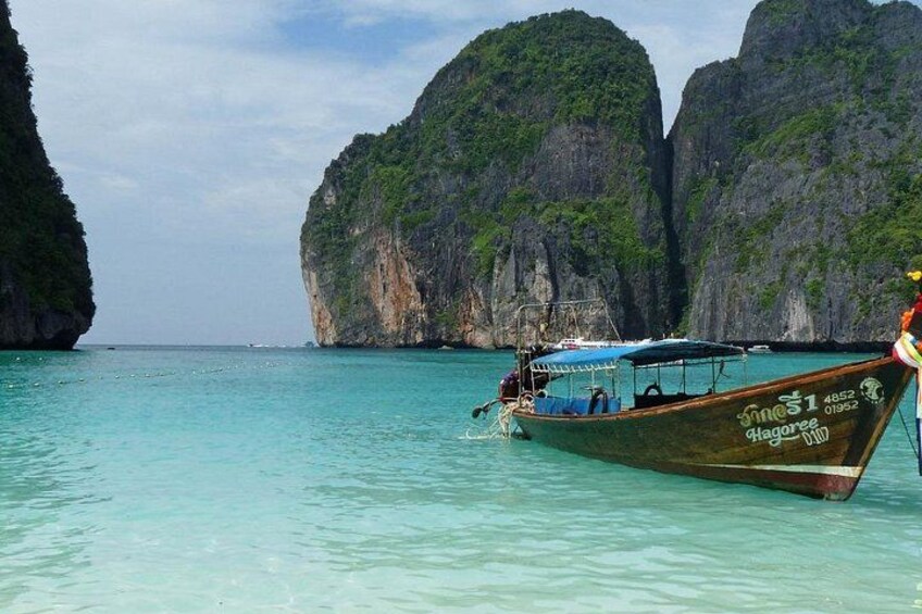 A boat named 'Hagocree' anchored near a rocky coastline with clear turquoise water. 2